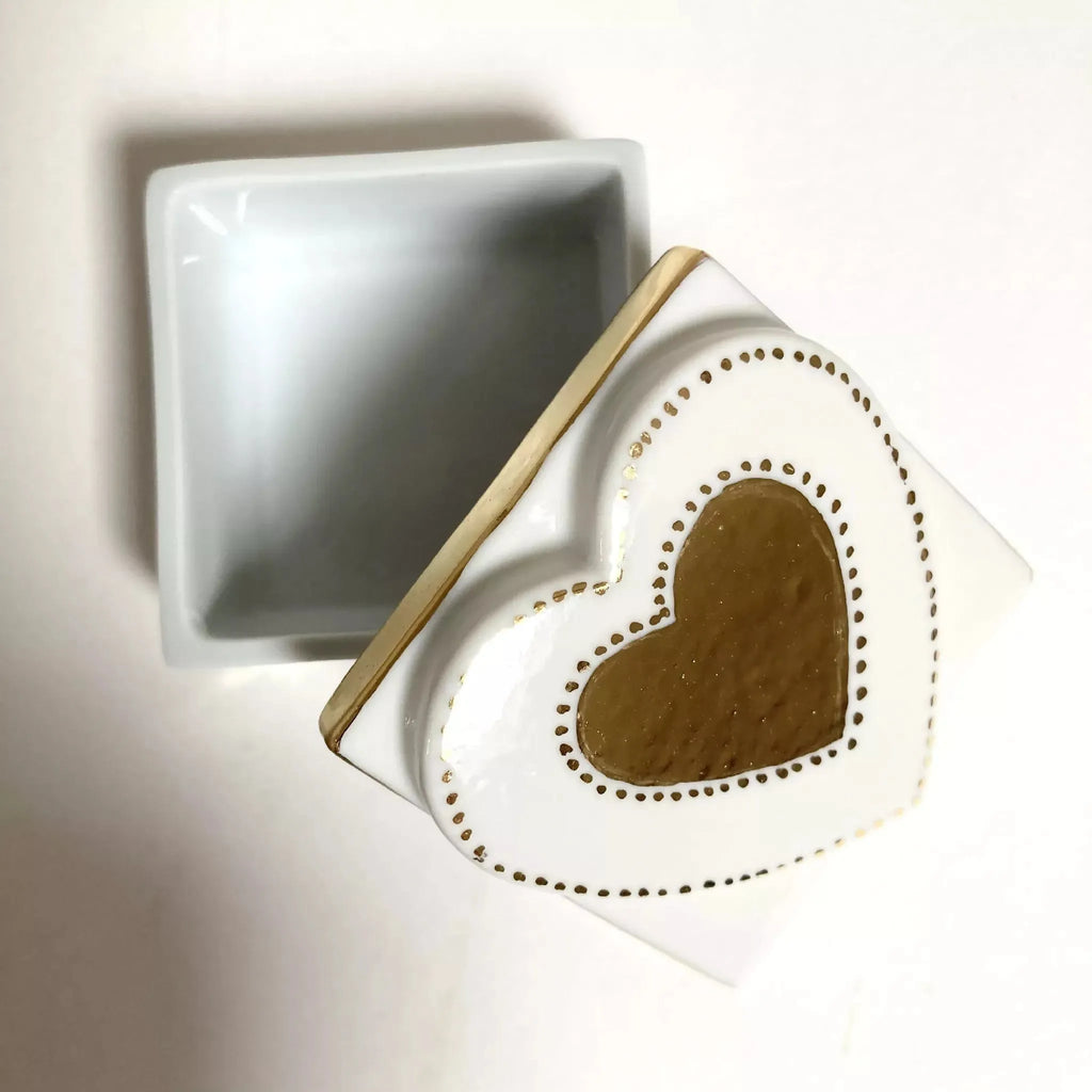 Boîte à bijoux blanche, couvercle ouvert, motif cœur doré au centre, intérieur gris