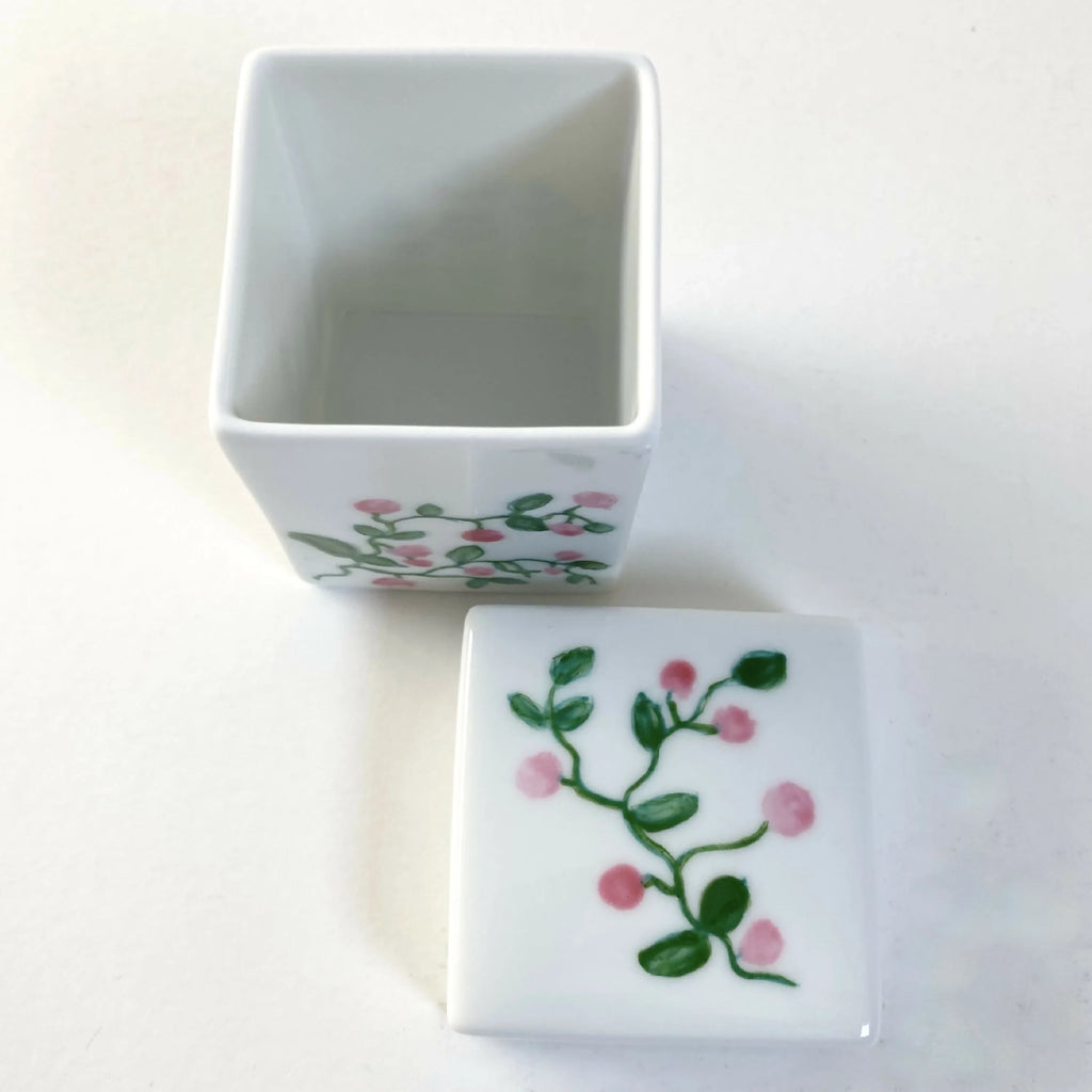 Boîte à bijoux en porcelaine blanche, couvercle ouvert, motif floral rose.