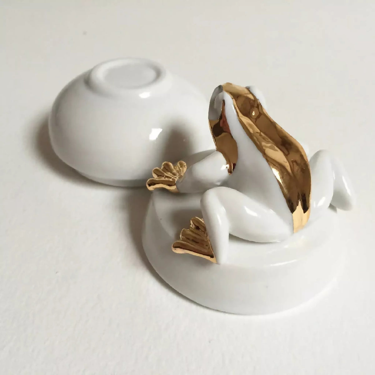 Boîte à bijoux grenouille blanche vue de profil, motifs dorés sur les pattes.