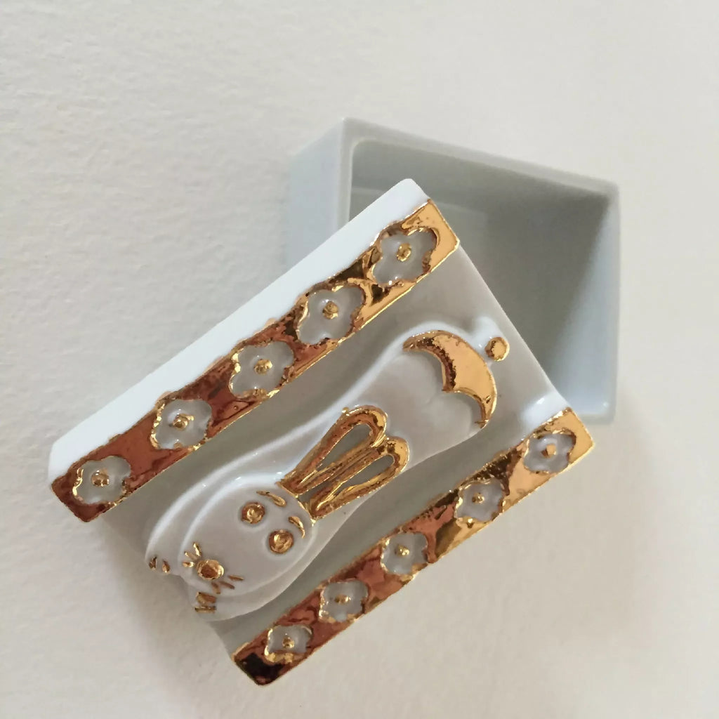 Boîte à bijoux lapin blanche, vue en biais, motifs dorés sur le clapet