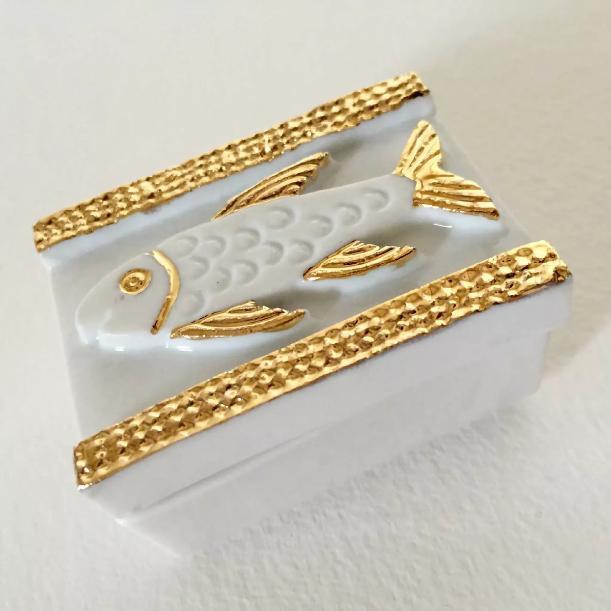 Boîte à bijoux blanche vue inclinée, motif poisson nacré et bordures dorées tressées