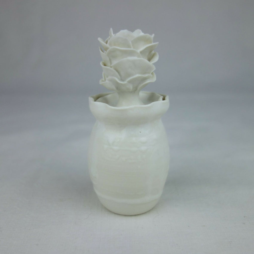Vase en céramique blanc, forme cylindrique avec fleurs en relief sur le dessus.
