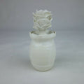 Vase en céramique blanc, forme cylindrique avec fleurs en relief sur le dessus.