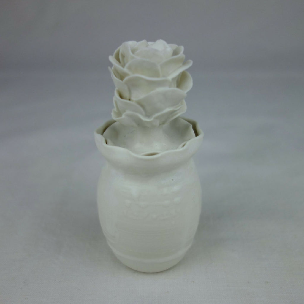 Vase en céramique blanc, fleurs en relief sur le dessus, vue arrière légèrement.