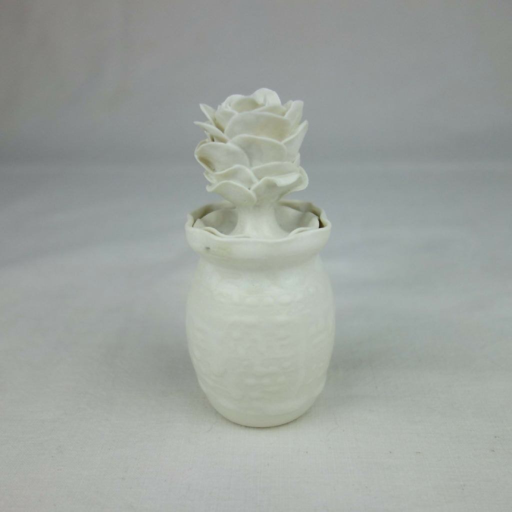 Vase en céramique blanc, fleurs en relief au sommet, vue entière centrée.