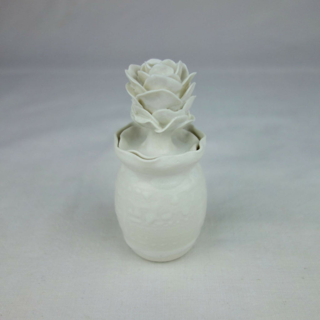 Vase en céramique blanc avec décoration florale en relief, vue de face légère.