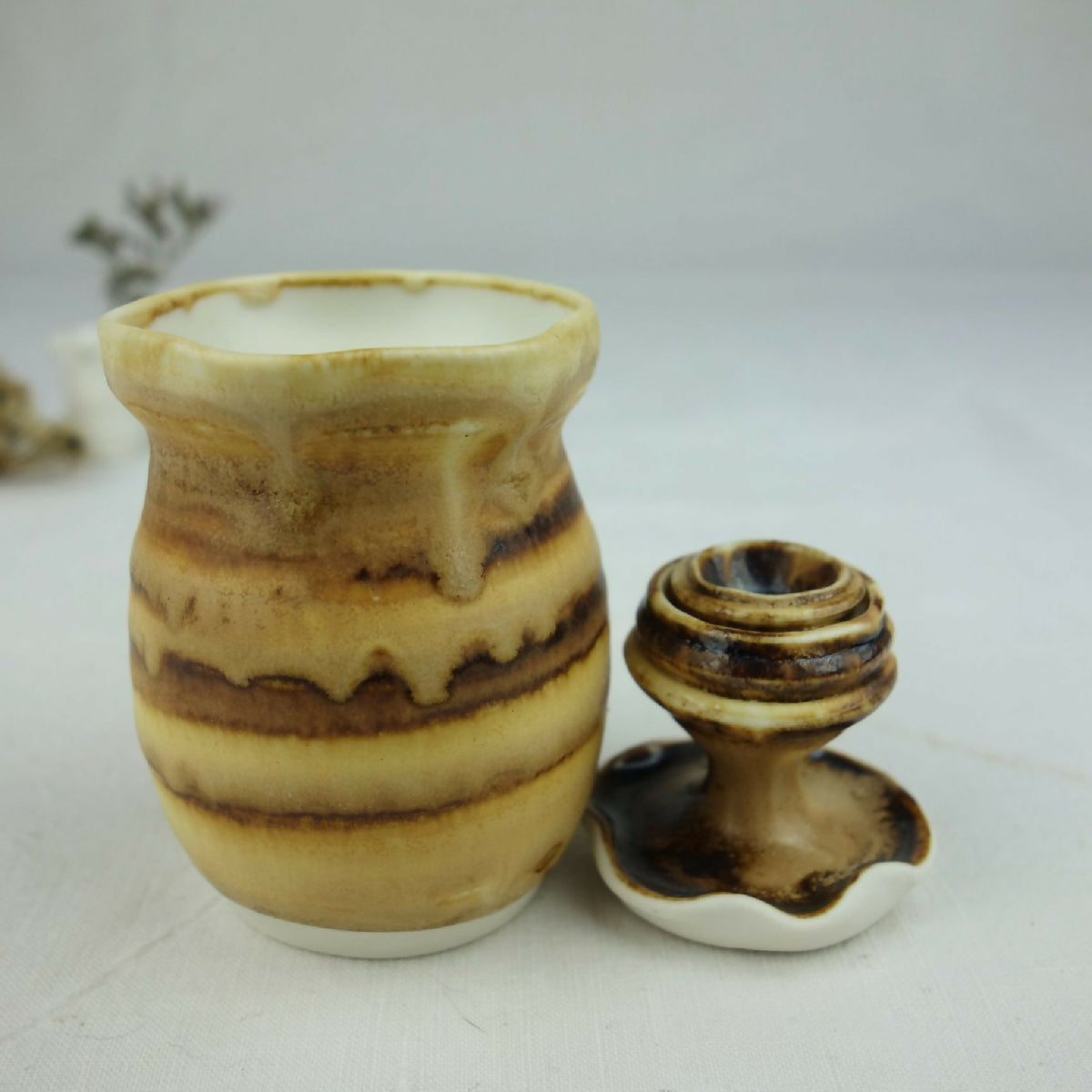 Petit pot en céramique beige et brun, motif marbré, vue de face avec base évasée