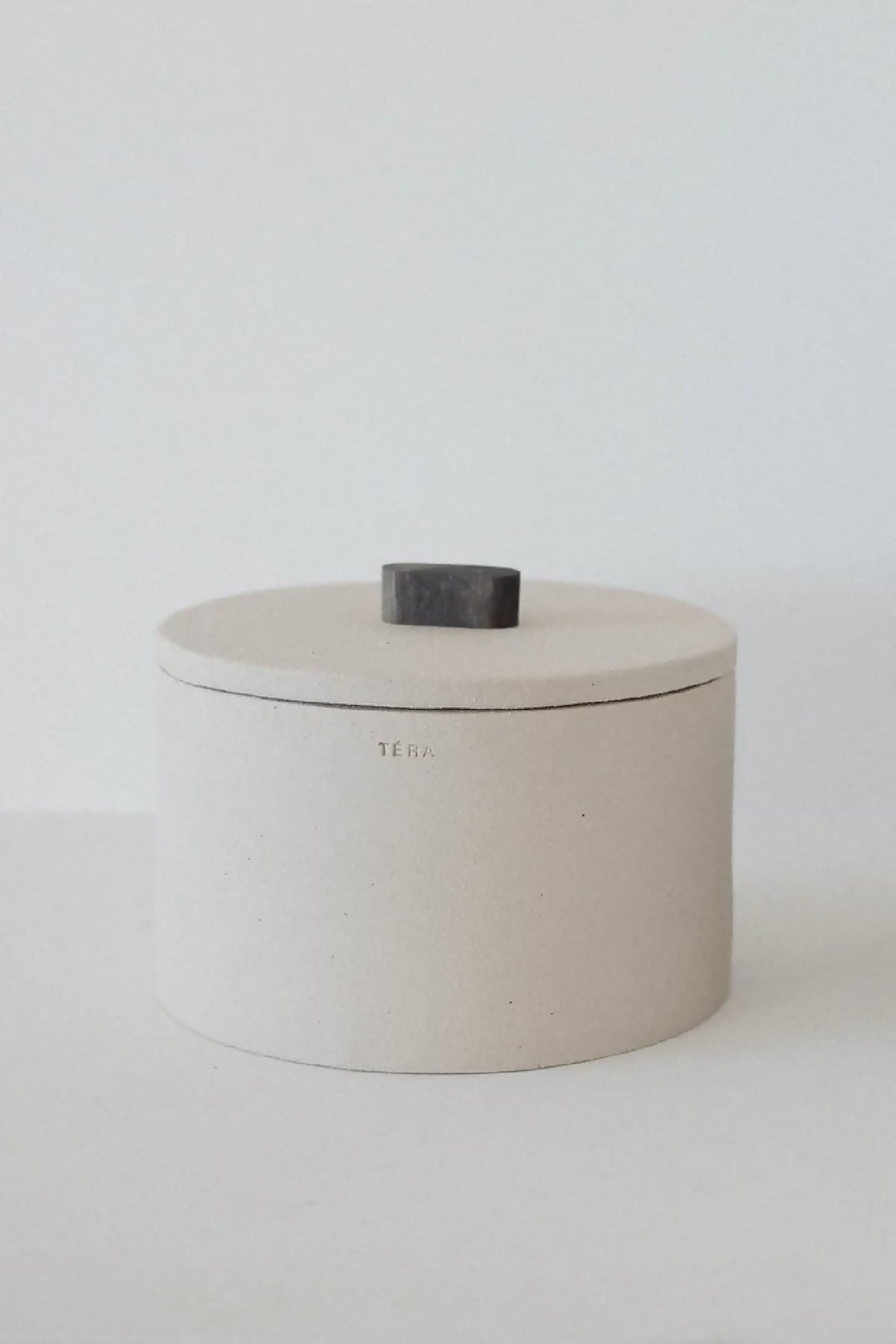 Boîte cylindrique beige TERA avec couvercle noir et logo discret