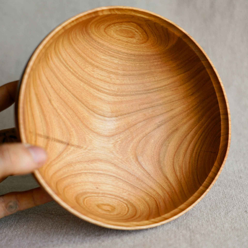 Saladier en bois de noisetier vu de l’intérieur, veines en spirales et texture.