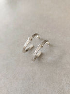 Boucles d’oreilles courbes en métal argenté, vues de face avec fermoirs