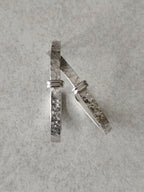 Boucles d’oreilles courbes argentées, une vue latérale sur la texture martelée