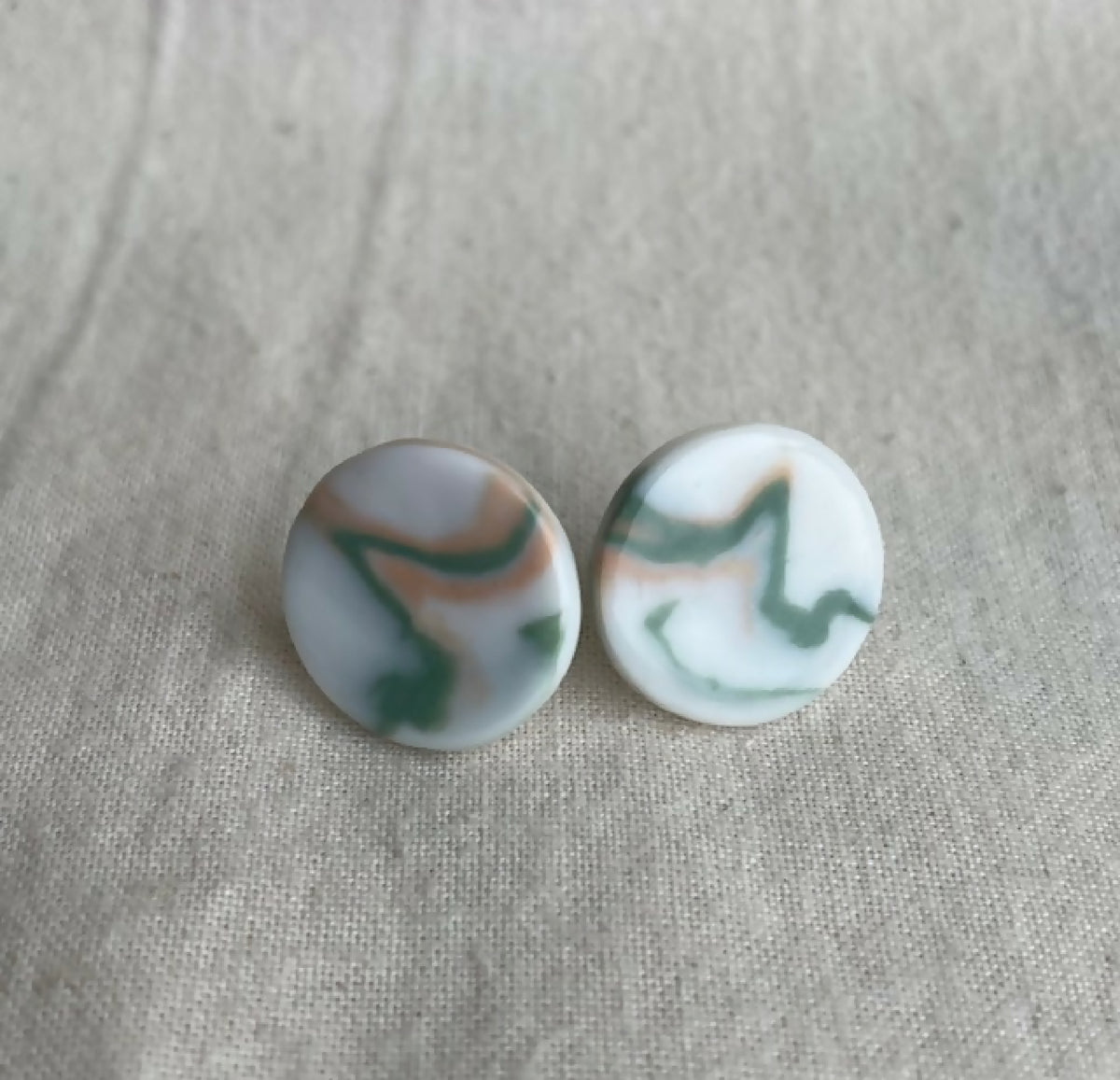 Paire de clous d’oreille en porcelaine blanche, motifs vert et rose abstraits.