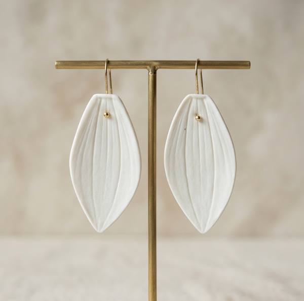 Boucles d’oreille Marie Courtillat en porcelaine blanche, pampilles ovales sur tiges dorées.
