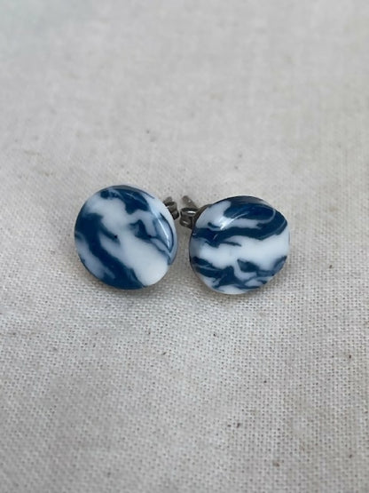 Clous d’oreilles en porcelaine, disques marbrés bleu et blanc, avec tige métallique.