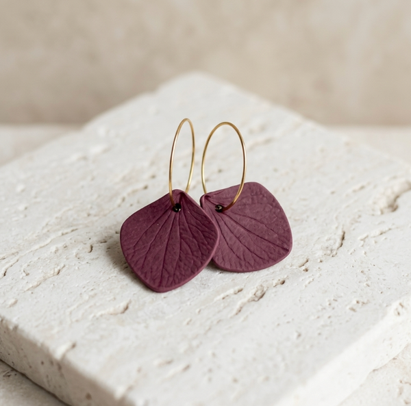 Boucles d’oreilles créoles avec pampilles en cuir violet prune sur anneaux dorés.