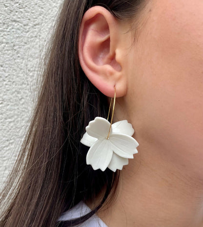 Créoles dorées et fleurs en porcelaine blanche, portées sur oreille