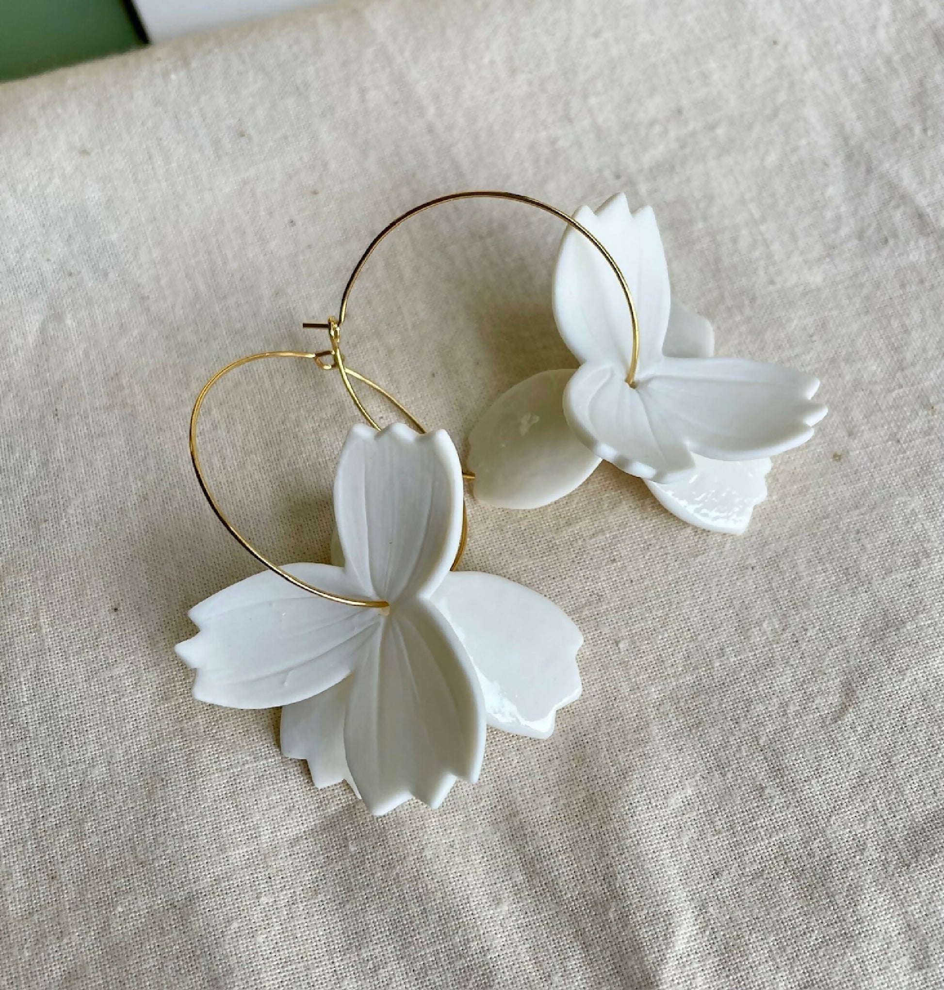 Paire de créoles dorées avec fleurs en porcelaine blanche, vue rapprochée