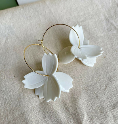 Paire de créoles dorées avec fleurs en porcelaine blanche, vue rapprochée