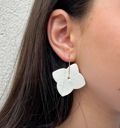 Créoles fleuries en porcelaine blanche, vues de profil sur l’oreille.