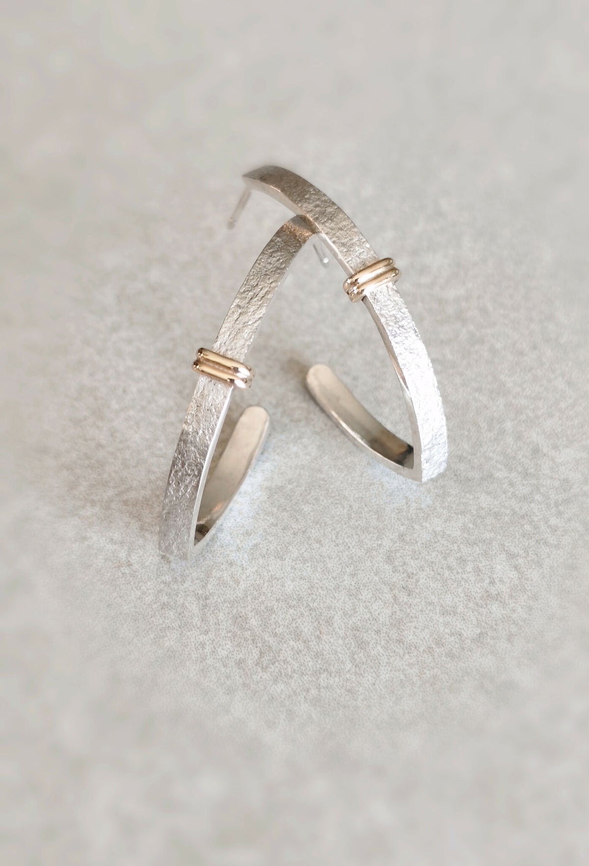 Boucles d’oreilles courbes argentées, détails du fermoir doré et intérieur poli