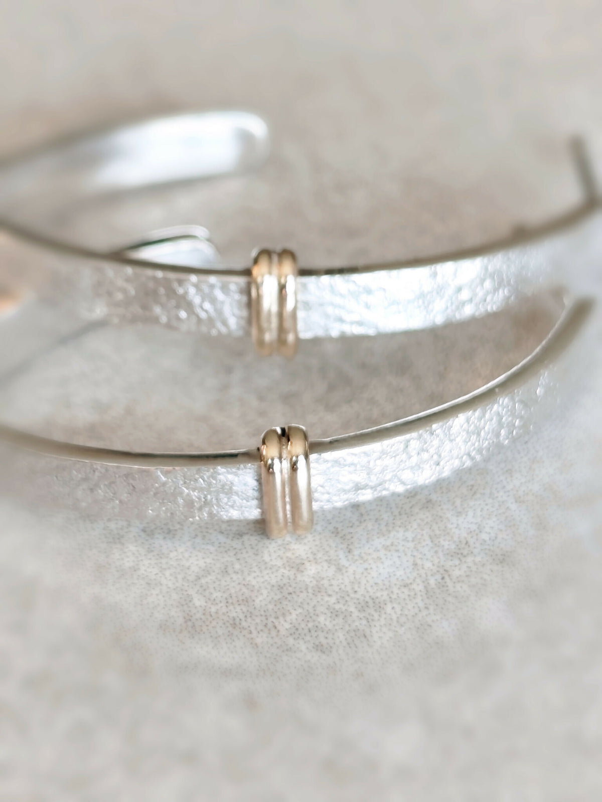 Détails des boucles d’oreilles courbes argentées : fermoirs dorés et surface texturée