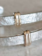 Gros plan sur les boucles d’oreilles courbes : anneaux dorés et reflets argentés