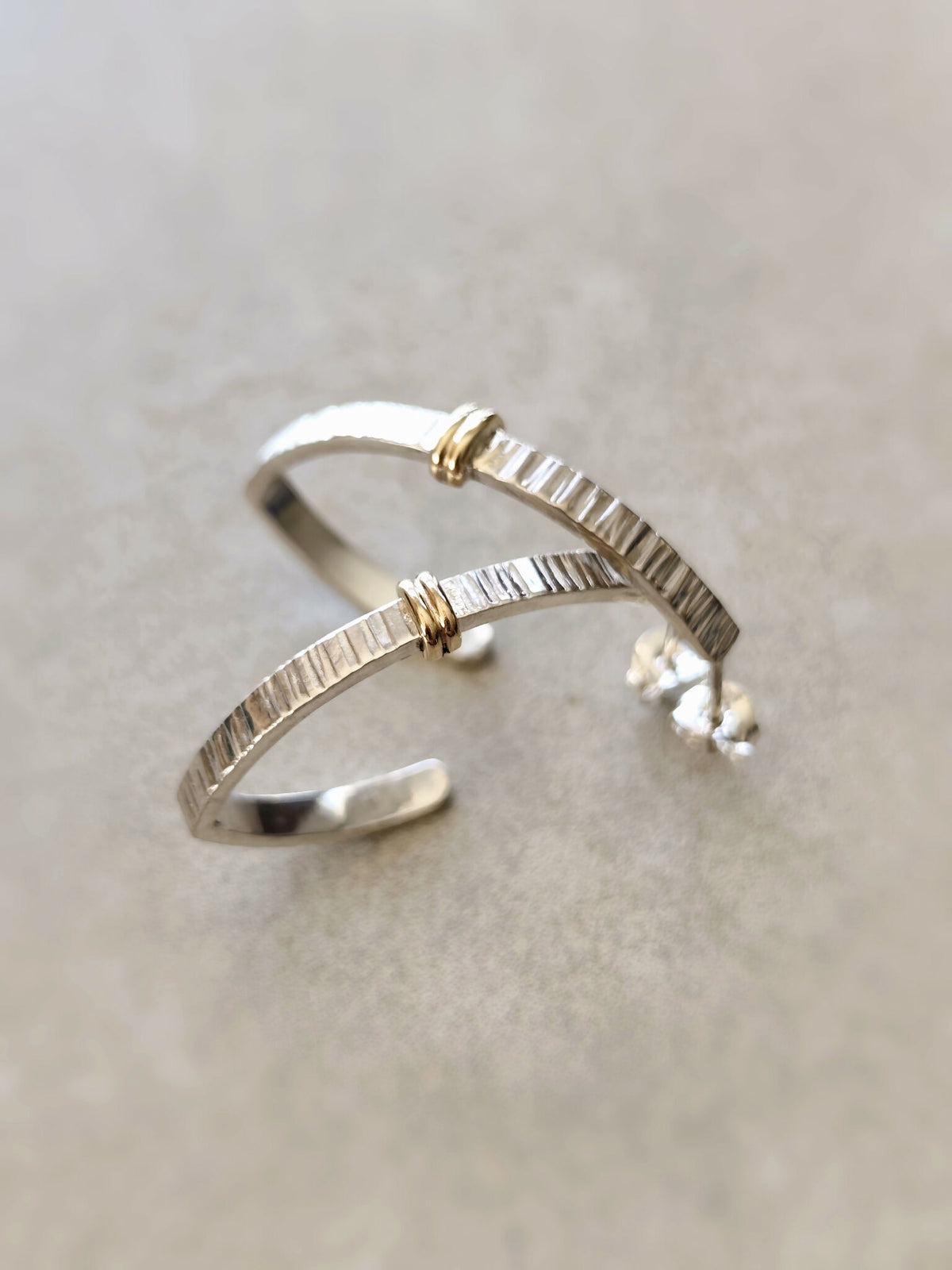 Boucles d’oreilles courbées argentées, inserts dorés, fermoir visible, finition brillante