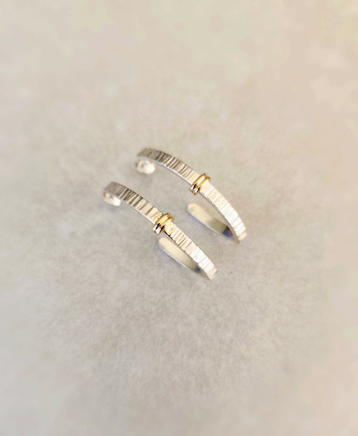 Boucles d’oreilles courbées argentées, fines rayures et inserts dorés, fermoir discret