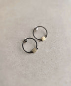 Boucles d’oreilles anneaux noirs, carrés texturés dorés, vue de dessus