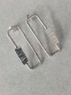 Boucles d’oreilles rectangulaires argentées, gros plan des textures à rayures.