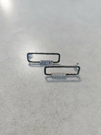 Boucles d’oreilles rectangulaires, plaquettes striées et reflets argentés, vue rapprochée