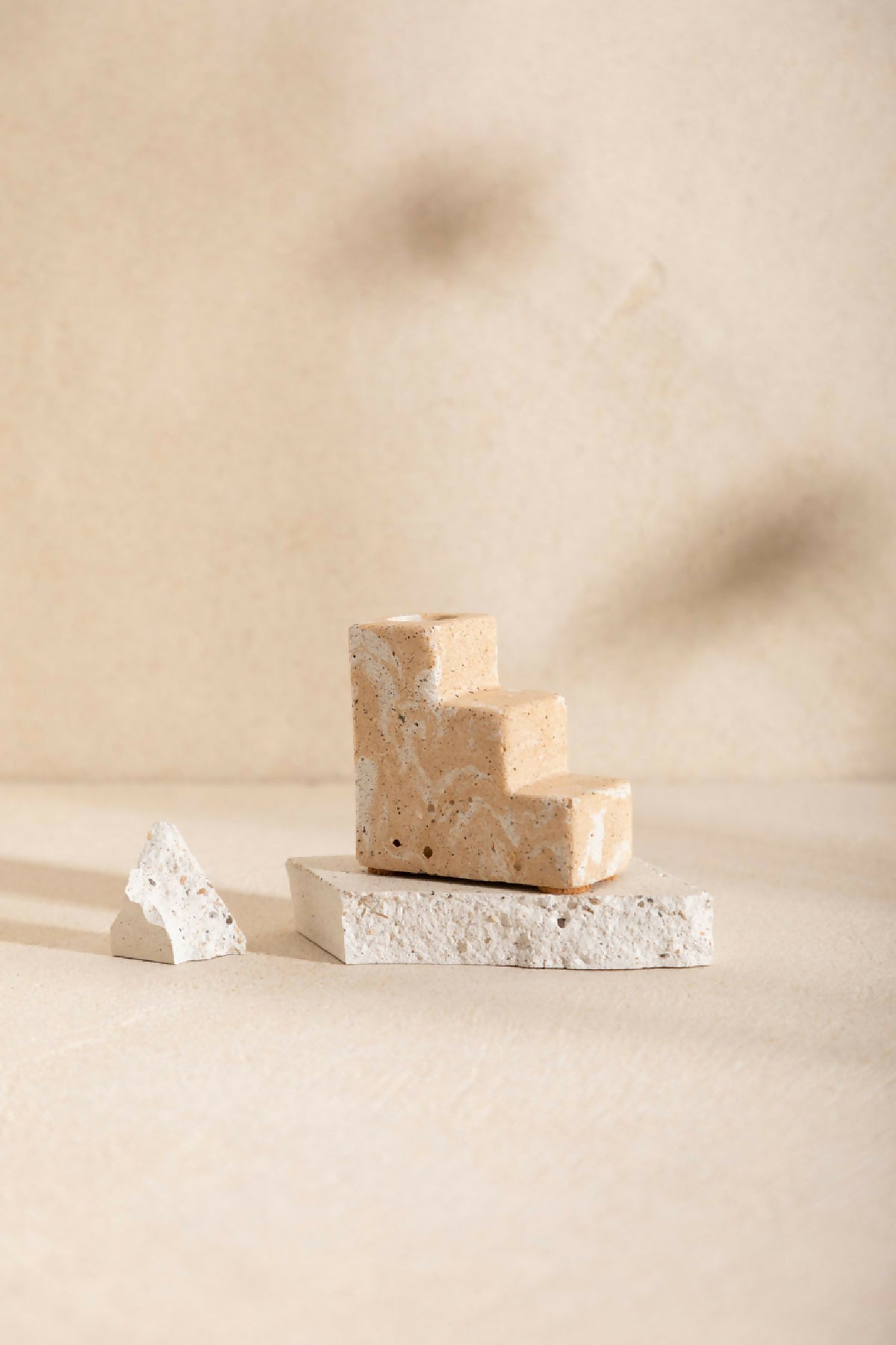 Bougeoir à base en blocs beige sable, socle en pierre claire texturée, sans bougie