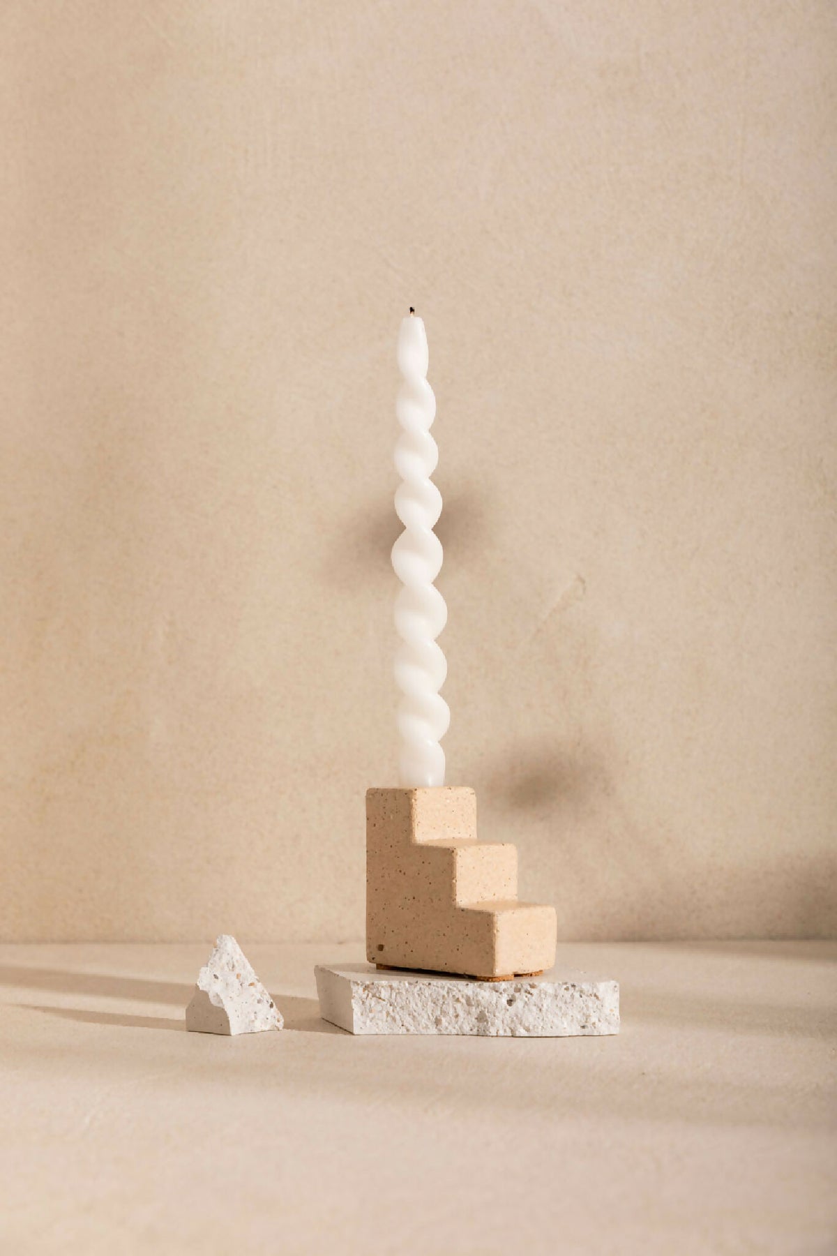 Bougeoir à bougie torsadée blanche, base beige en blocs carrés sur socle texturé