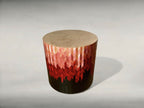 Bout de canapé rond en tissu : dessus beige, motif chevrons rouge sur base sombre.
