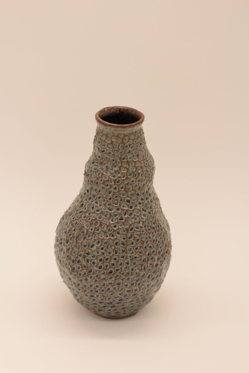 Petite bouteille en céramique bleu-gris à texture granuleuse, goulot brun