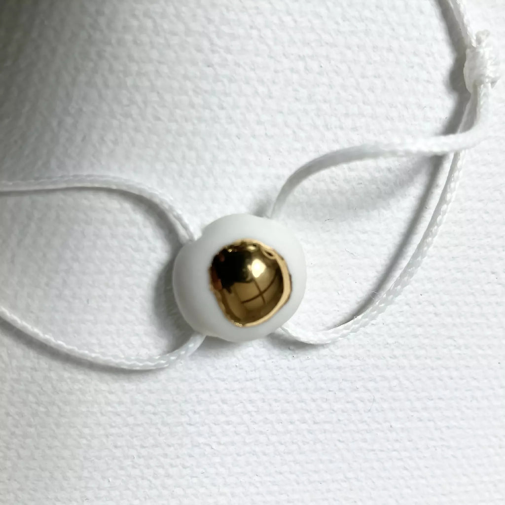 Bracelet goutte d’or : perle ronde dorée sur cordon blanc