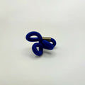 Broche en entrelacs de tissu bleu et tige métallique dorée.