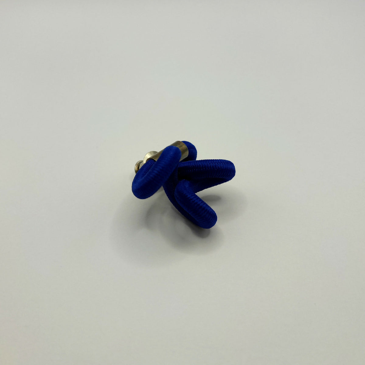 Broche en tissu bleu noué avec fermeture à l’arrière en métal doré.