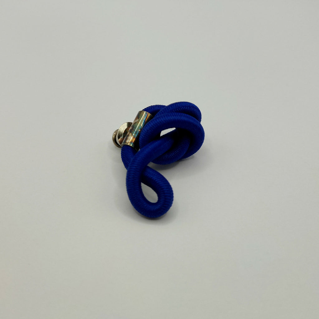 Broche en entrelacs de tissu bleu, attache métallique argentée.