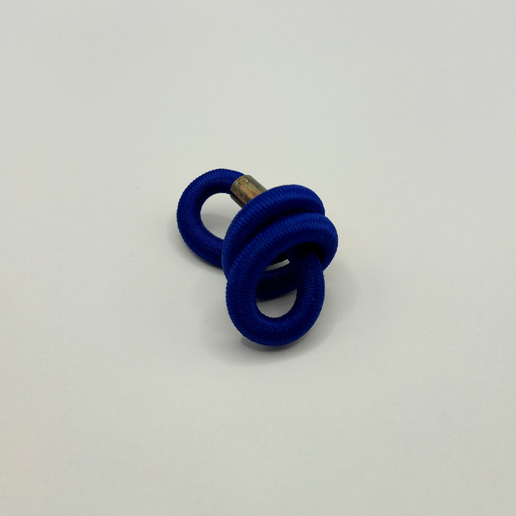 Broche en tissu bleu en forme d’entrelacs, épingle dorée et anneaux.