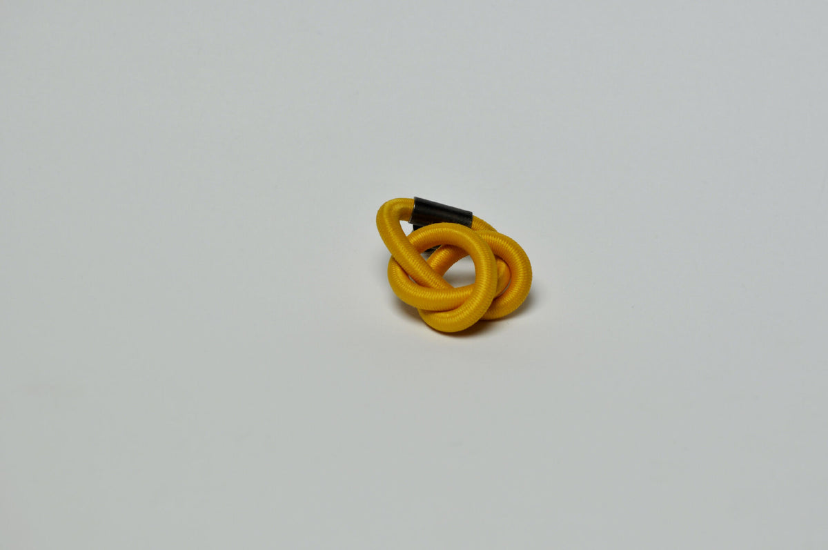 Broche entrelacée jaune, nœud de boucles concentriques.