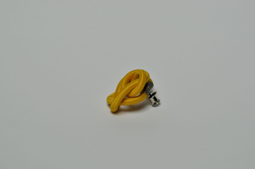 Broche entrelacée jaune avec attache métallique, vue inclinée.