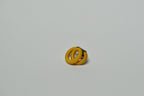 Broche entrelacée jaune, fermoir noir partiellement visible.