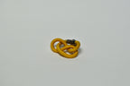 Broche entrelacée jaune, attache métallique visible à l’arrière.