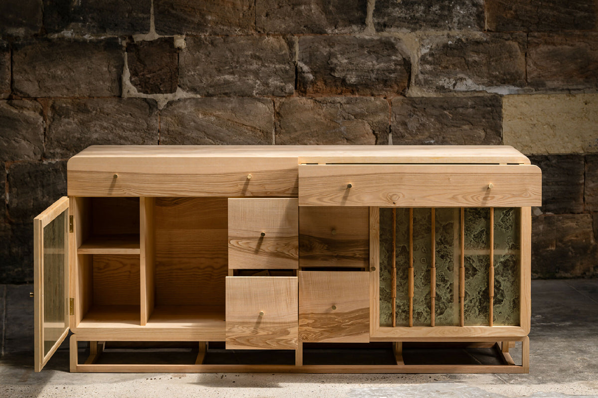 Buffet en bois clair avec portes à lames verticales et compartiments ouverts