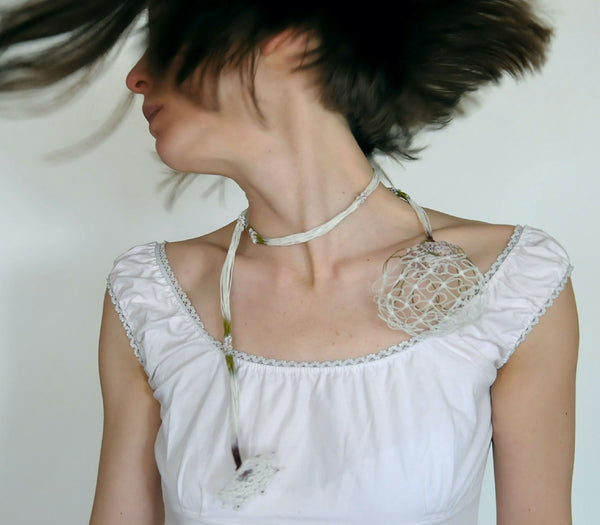 Collier en soie blanc à cordons torsadés, petite fleur brodée au centre.