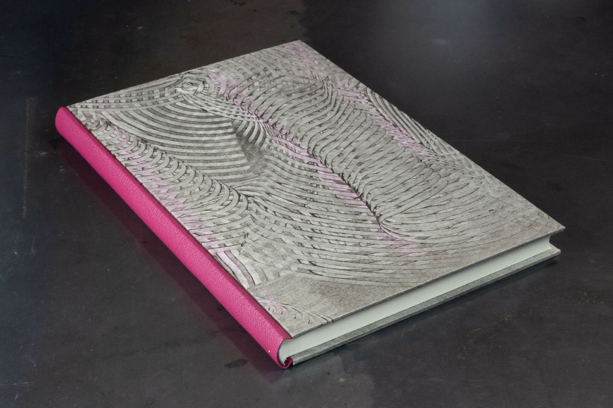 Cahier à couverture cuir gris clair, motifs ondulés, dos fuchsia en cuir.