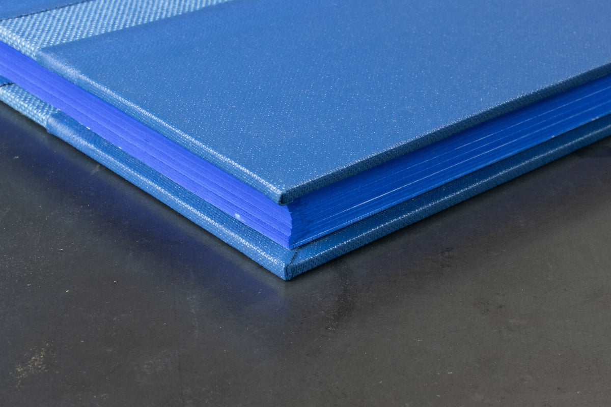 Livre d’or bleu clair en tissu, vue latérale des tranches et du dos.