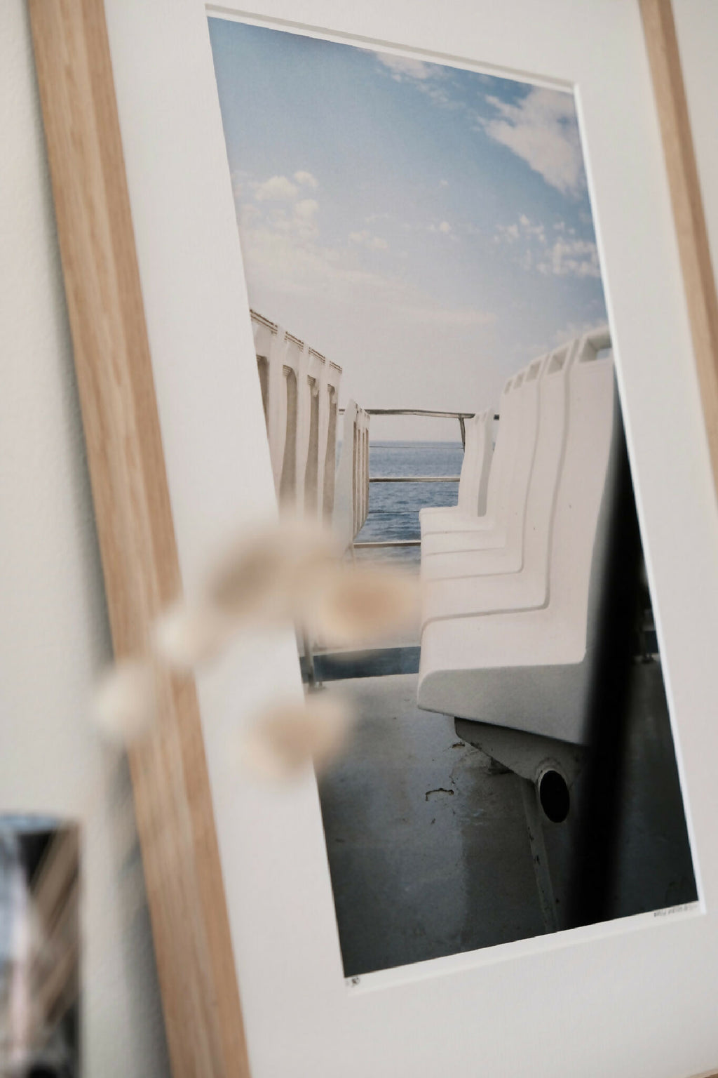 Photo encadrée inclinée, chaises longues blanches et mer au loin