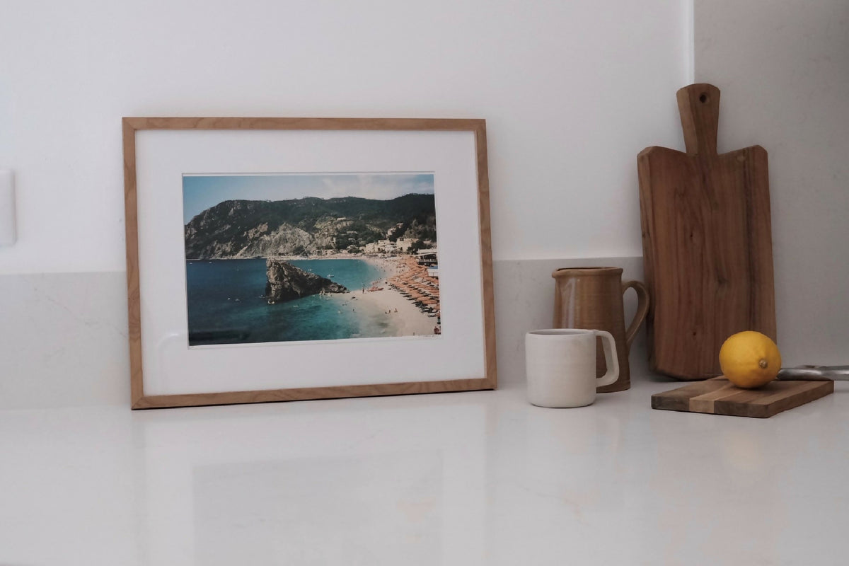 Affiche encadrée avec vue plage et falaises, tons bleus et sable.